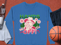 The Garment Graphics Wild Side Sweatshirt, unisex, boasts bold graphics of a hat-wearing figure pointing amid flowers with HANDS OFF! in bright green and red. Its styled on an orange backdrop with a water bottle, towel, black shorts, and a basketball.