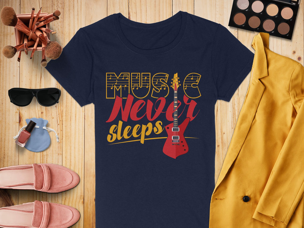 A Garment Graphics navy Music Never Sleeps t-shirt with a guitar graphic lies on a wooden surface, accompanied by a yellow jacket, sunglasses, makeup brushes, an eyeshadow palette, cream slippers, and a perfume bottle.