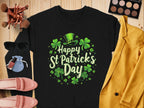 Flat lay of a black Garment Graphics sweatshirt with shamrocks and a leprechaun hat for St. Patricks Day, surrounded by a yellow jacket, pink shoes, sunglasses, makeup brushes, and an eyeshadow palette on wood.