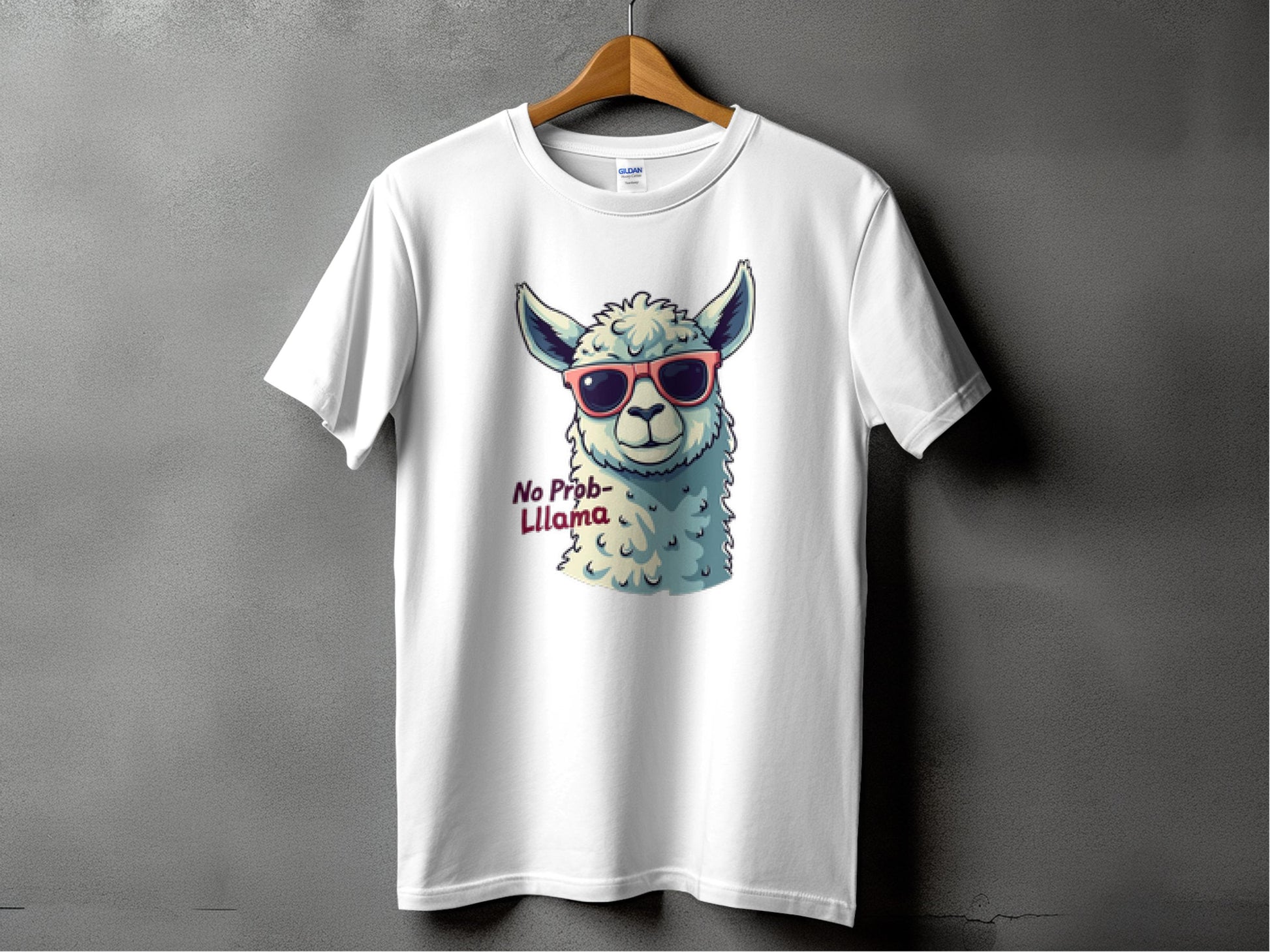 The Garment Graphics White Llama T-shirt for all family sizes displays a cartoon llama sporting red sunglasses with the phrase No Prob-llama next to it, hanging against a plain gray wall.