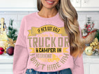 A person in a humorous pink Garment Graphics sweatshirt that reads If hes got golf clubs in his truck or a camper in his driveway, dont hire him. stands in a kitchen decorated with holiday ornaments and small trees.
