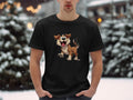 A dog lover stands outside wearing a black Garment Graphics T-shirt adorned with an animated cartoon dog, surrounded by snow-covered trees and blurred lights, capturing winters magical essence.
