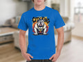 Someone is wearing a blue Garment Graphics T-Shirt with a distinctive crowned bulldog design above bold CITY KING text on an orange and yellow background, in a room with blurred furniture.