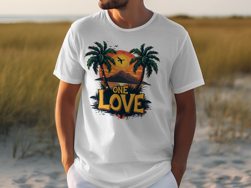 A person in a Garment Graphics white cotton T-shirt featuring two palm trees, a tropical sunset, a mountain, and a plane with One Love in bold yellow and black letters stands outdoors on grass, perfect for beach lovers dreaming of distant shores.