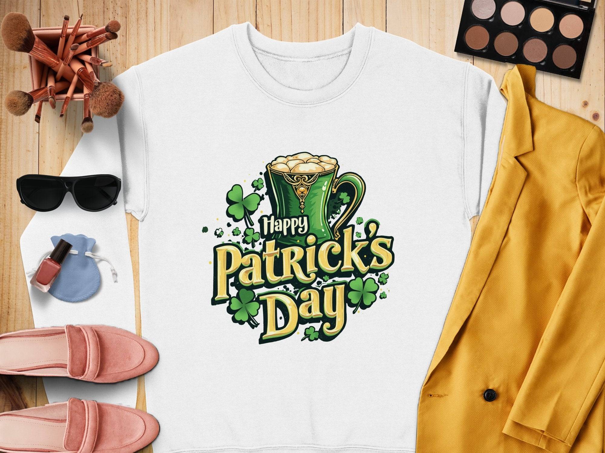 Garment Graphics offers a vibrant St. Patricks Day sweatshirt with a festive green mug graphic, frothy delights, and clovers, paired with sunglasses, makeup brushes and palette, pink shoes, a yellow jacket, nail polish, and a blue pouch.
