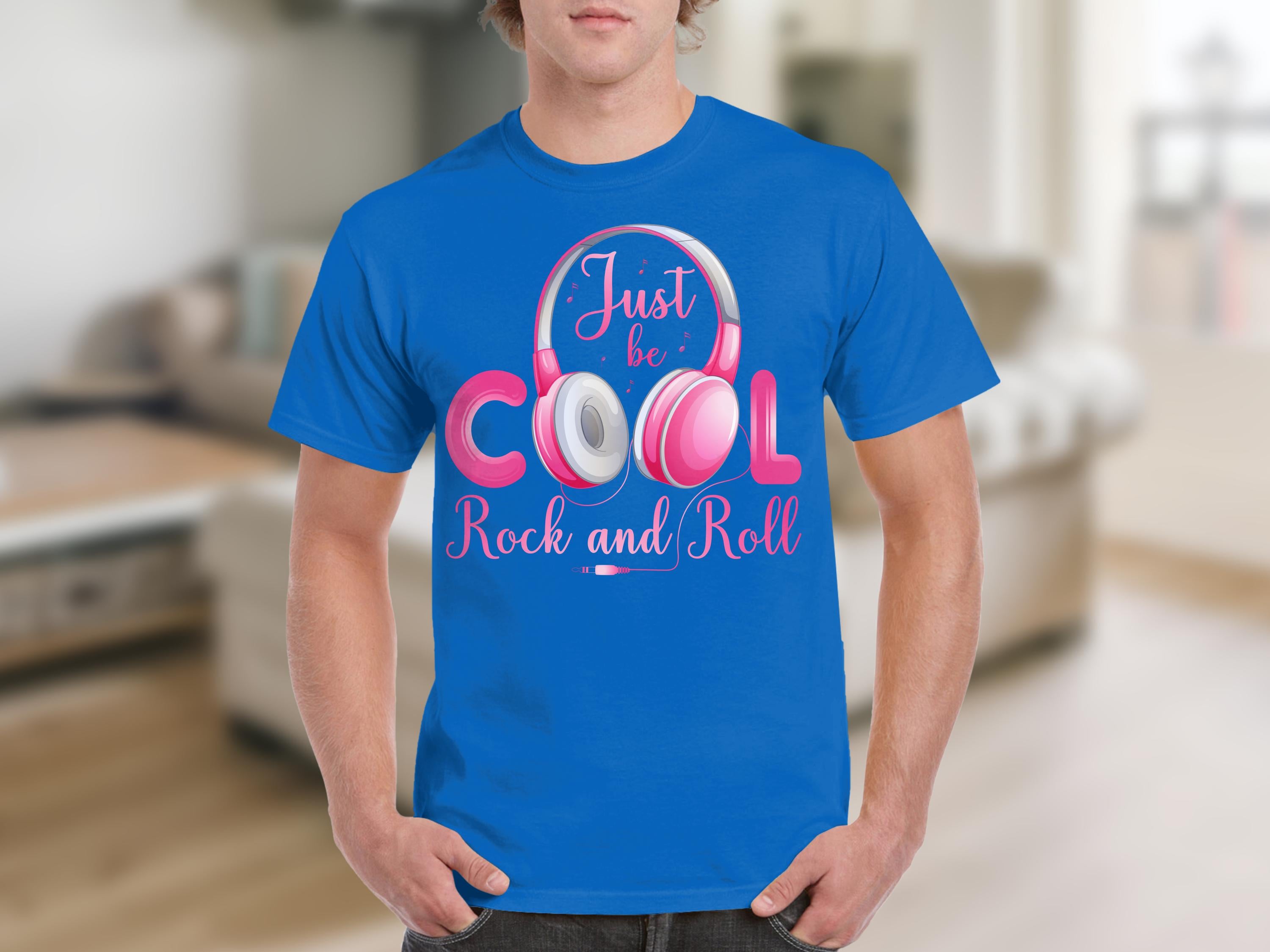 Someone wearing a bright blue Garment Graphics t-shirt with Just be Cool Rock and Roll and pink white fun headphones around Cool displays their passion for rock and roll tees in a blurred modern room setting.