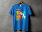 A Garment Graphics blue T-shirt with a DJ graphic, colorful paint splashes, and Dont Stop the Music text hangs on a wooden hanger against a gray background—ideal for music lovers seeking to make a statement.