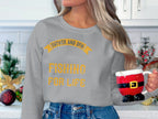 A person with long hair wearing a Garment Graphics graphic sweatshirt reading Father and Son Fishing for Life in yellow holds a Santa outfit-shaped mug. Christmas ornaments and greenery sit on the white countertop, capturing the festive spirit.