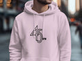 Someone is wearing a white Garment Graphics hoodie with 45 RPM on the front, ideal for vinyl enthusiasts. Standing on a street with blurred buildings behind them, they highlight their passion for graphic hoodies and vintage music.