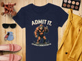 A navy Garment Graphics T-shirt with ADMIT IT BIGFOOT. LIFE WOULD BE BORING WITHOUT ME. pairs well with makeup brushes, eyeshadow, sunglasses, nail polish, pink loafers, a yellow blazer, and denim jeans. Ideal for quirky T-shirt enthusiasts!.