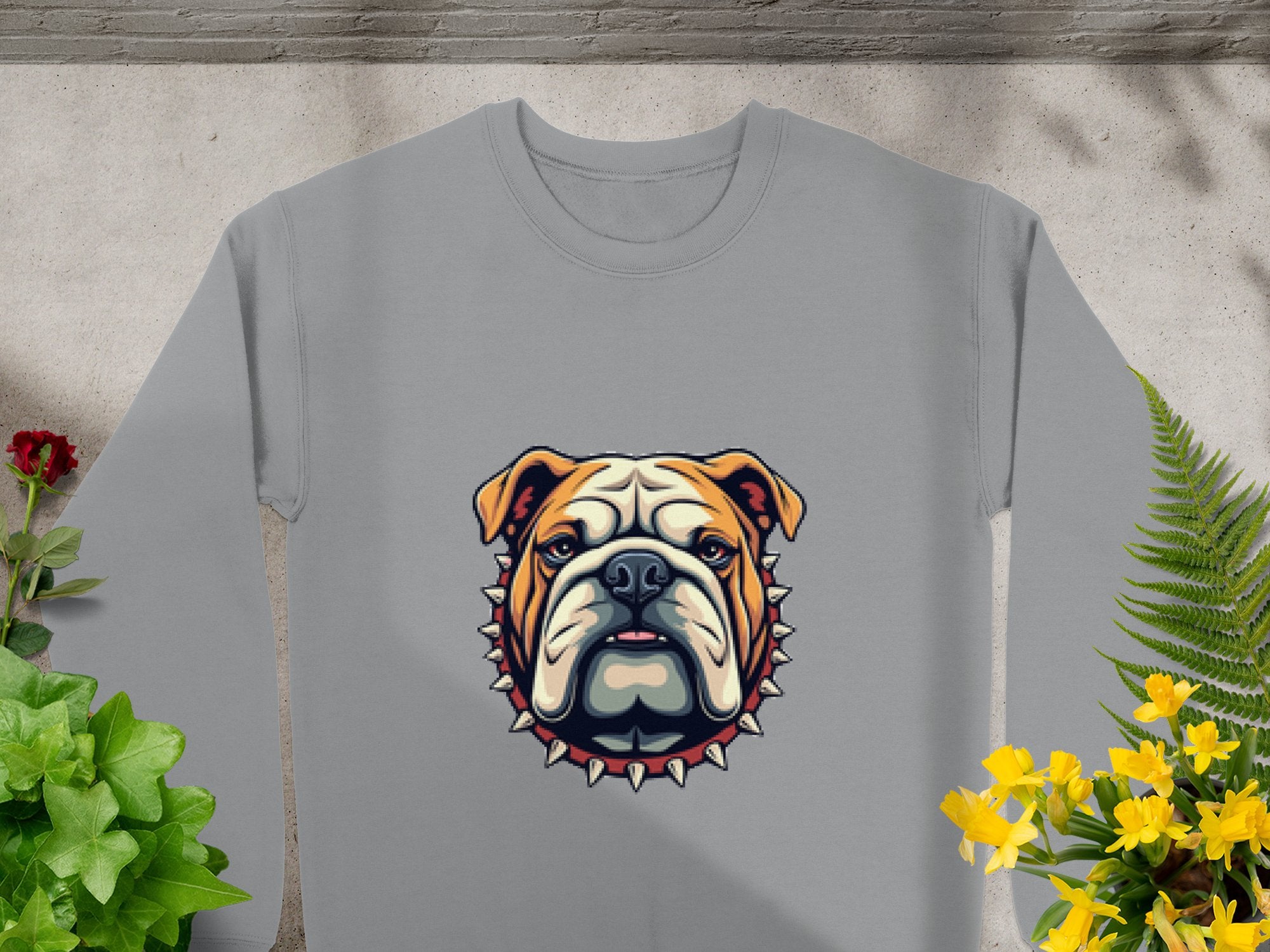 Garment Graphics presents a unisex gray sweatshirt featuring a bulldog with a spiked collar, elegantly displayed among red and yellow flowers with green leaves.