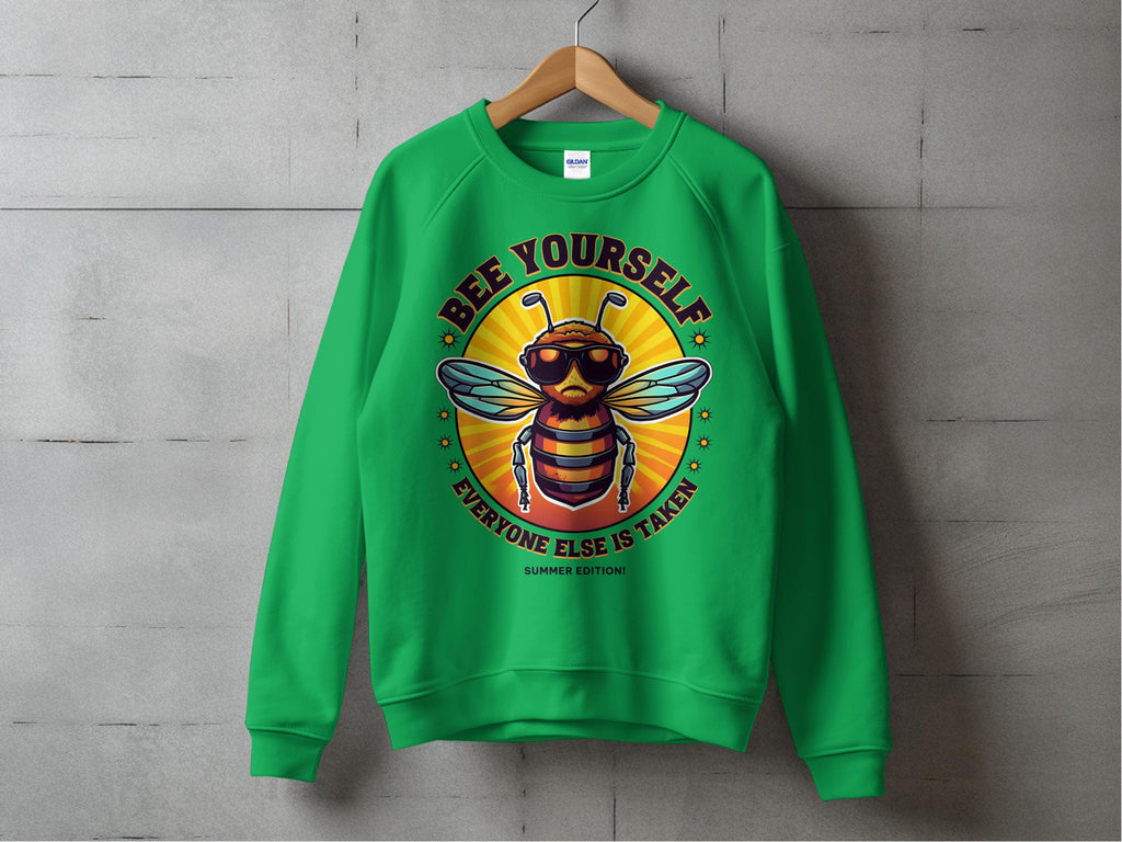 Garment Graphics Summer Edition Sweatshirt features a green design with a cartoon bee in sunglasses, BEE YOURSELF message, and an orange-yellow sunburst. Available in unisex sizes, this sweatshirt combines vibrant style with an uplifting mantra.
