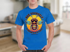 A person dons a blue T-shirt by Garment Graphics, showcasing a stylish bee with sunglasses. The shirt reads Bee Yourself, Every One Else Is Taken, Summer Edition. Its ideal for family sizing against a blurred indoor backdrop.