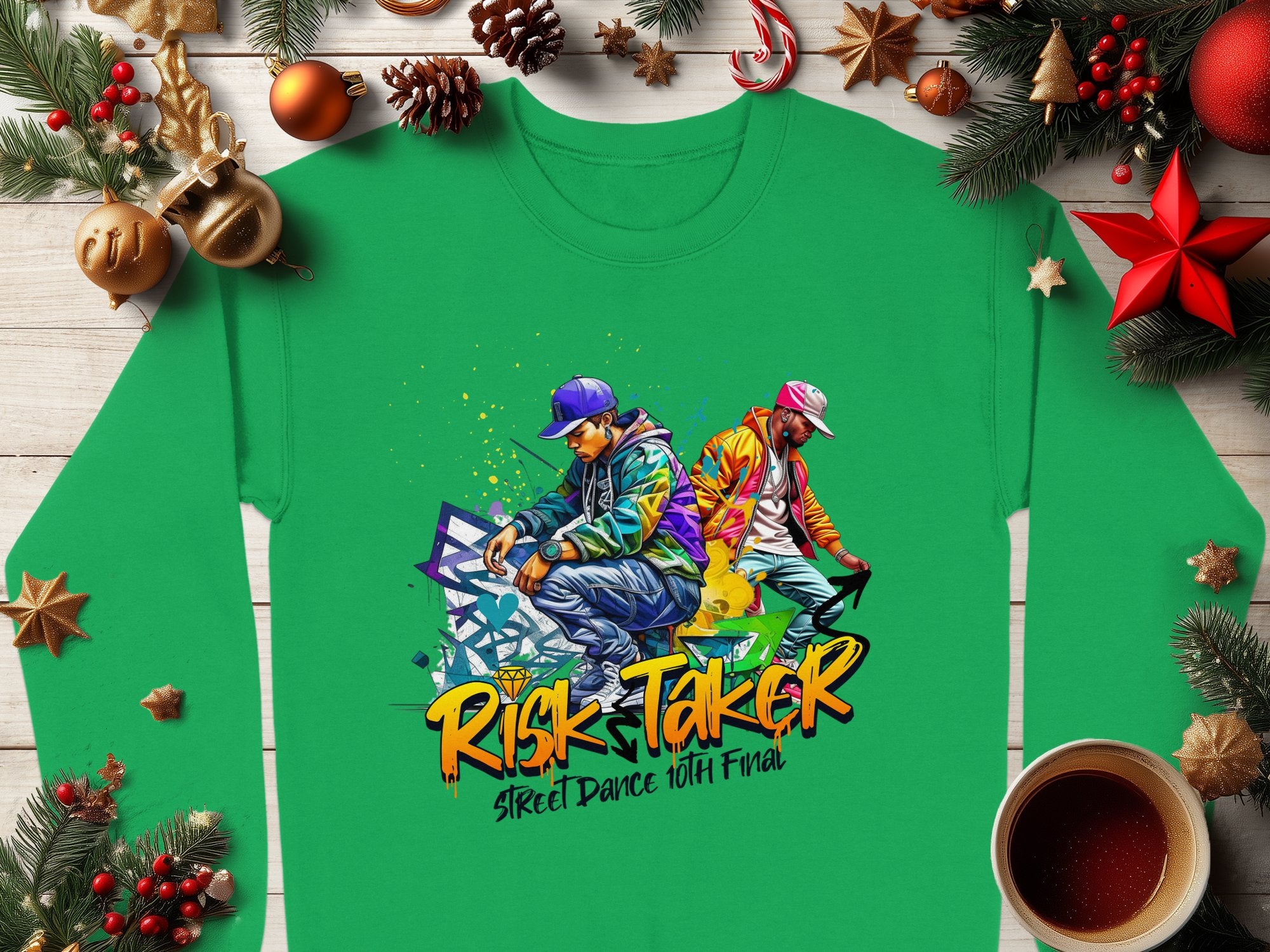 A green Garment Graphics sweatshirt showcases urban flair with two dancers in streetwear amid graffiti art, featuring the text Risk Taker Street Dance 10th Final. Unisex sizing offers a great fit. It sits on wood with festive decor.
