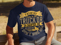 A man sits on a wooden bench wearing a Garment Graphics dark blue t-shirt with the humorous quote, If hes got golf clubs in his truck or a camper in his driveway, I dont hire him, and an illustration of a truck—ideal for those who appreciate humor and unique attire.