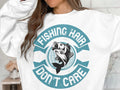 A woman wears a white Garment Graphics fishing sweatshirt featuring a vibrant fish jumping design and the phrase Fishing hair dont care in teal, embodying her passion for fishing. Her long hair cascades down, slightly hiding her face.