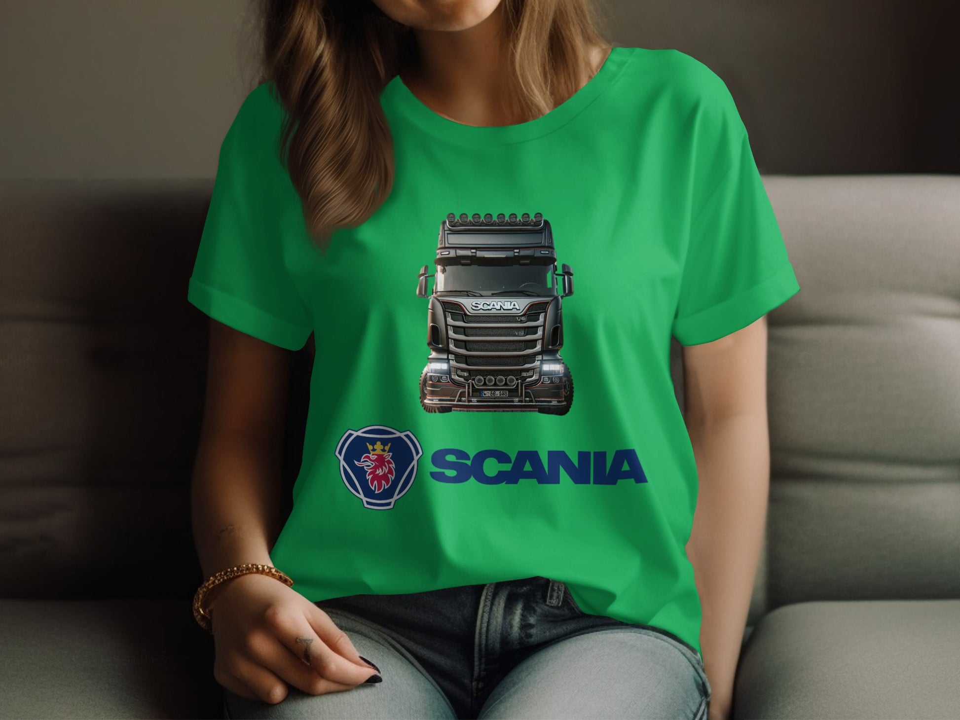 A person lounges on a couch in a green graphic T-shirt by Garment Graphics, featuring a large truck with the Scania logo and name. Ideal for automotive enthusiasts, this stylish Scania T-shirt complements any relaxation time. The wearer is partially visible from the shoulders down.