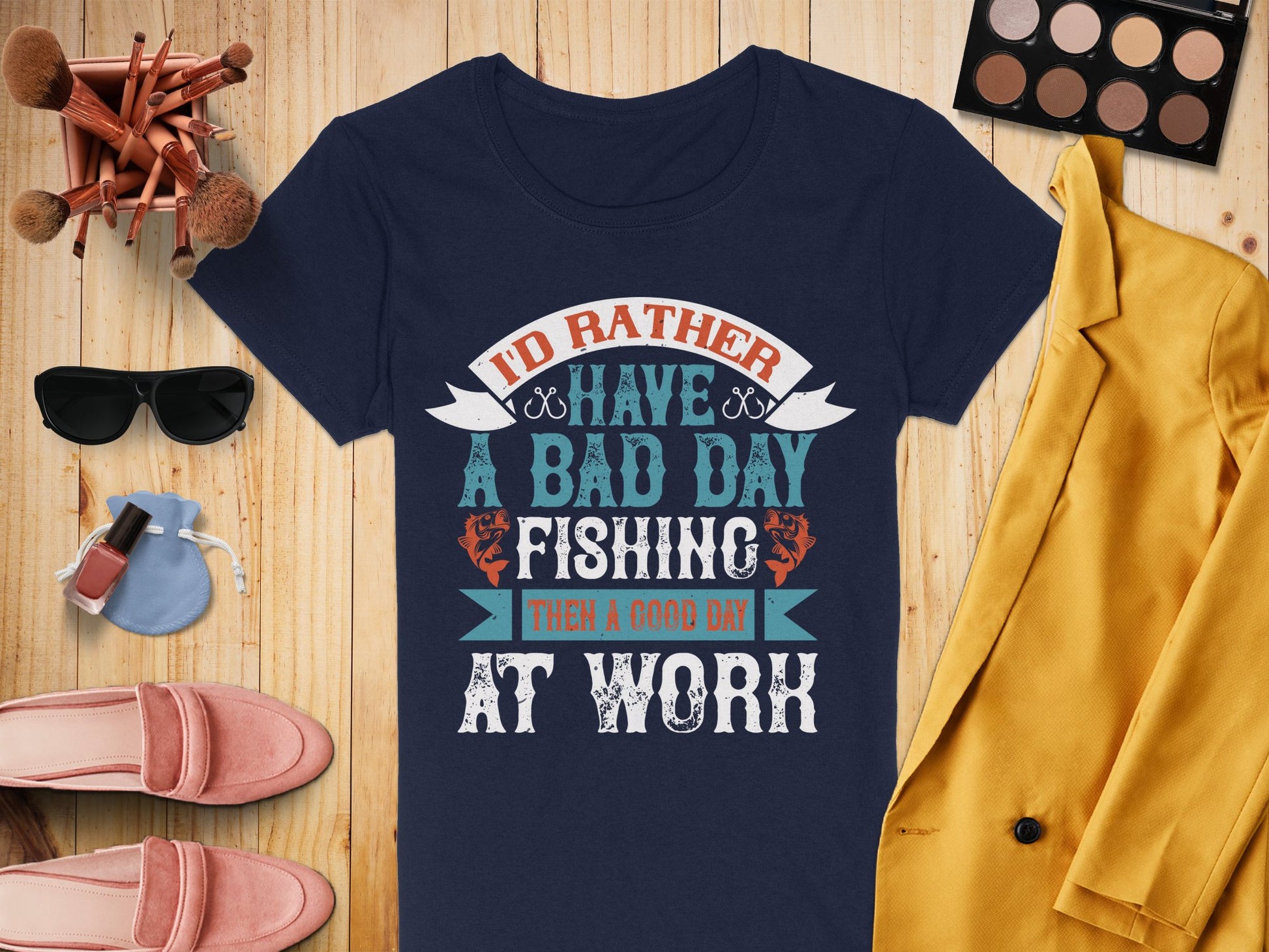 A Garment Graphics navy fishing T-shirt reads Id rather have a bad day fishing than a good day at work. Its artfully displayed with makeup, pink shoes, a yellow blazer, and a light blue purse, ideal for fishing enthusiasts in womens sizing.