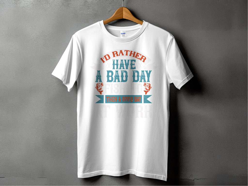 Garment Graphics white fishing T-shirt features Id rather have a bad day fishing than a good day at work in orange and teal fonts. Ideal for anglers, it hangs on a wooden hanger against a gray background, making it an excellent gift for any fishing enthusiast.
