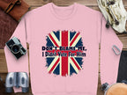 A unisex pink sweatshirt by Garment Graphics, showcasing a British flag and the phrase Dont Blame Me, I Didnt Vote For Him, lies on a wooden surface with a camera, binoculars, a watch, and leather accents.