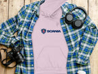 A trendy apparel scene features a pink Garment Graphics hoodie under a blue and green plaid shirt on wood. Nearby are black headphones, a white cup, and a black camera, completing the stylish setup.