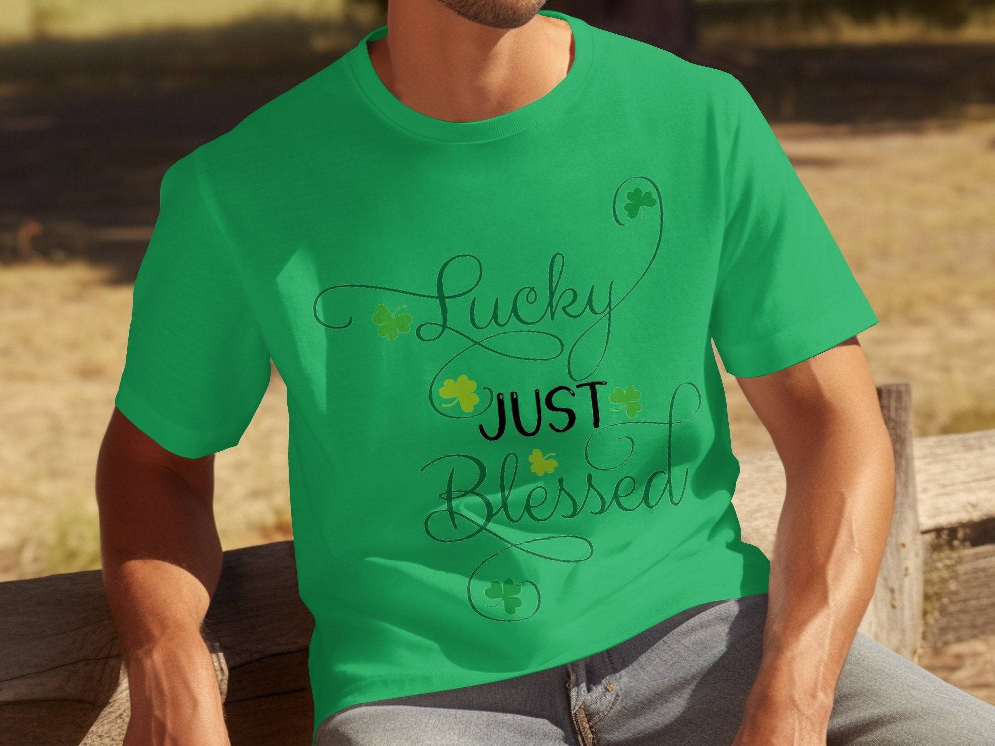 A person sits on a wooden bench, highlighting a classic fit, green graphic T-shirt from Royal Mail - 24 Tracked featuring Lucky Just Blessed with small shamrocks. The blurred outdoor background enhances the charm of this lucky attire.