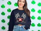 A person sports a vibrant Garment Graphics sweatshirt featuring a racing car and checkered flags, standing against a wall of green shamrocks, perfectly embodying motorsport enthusiasm.