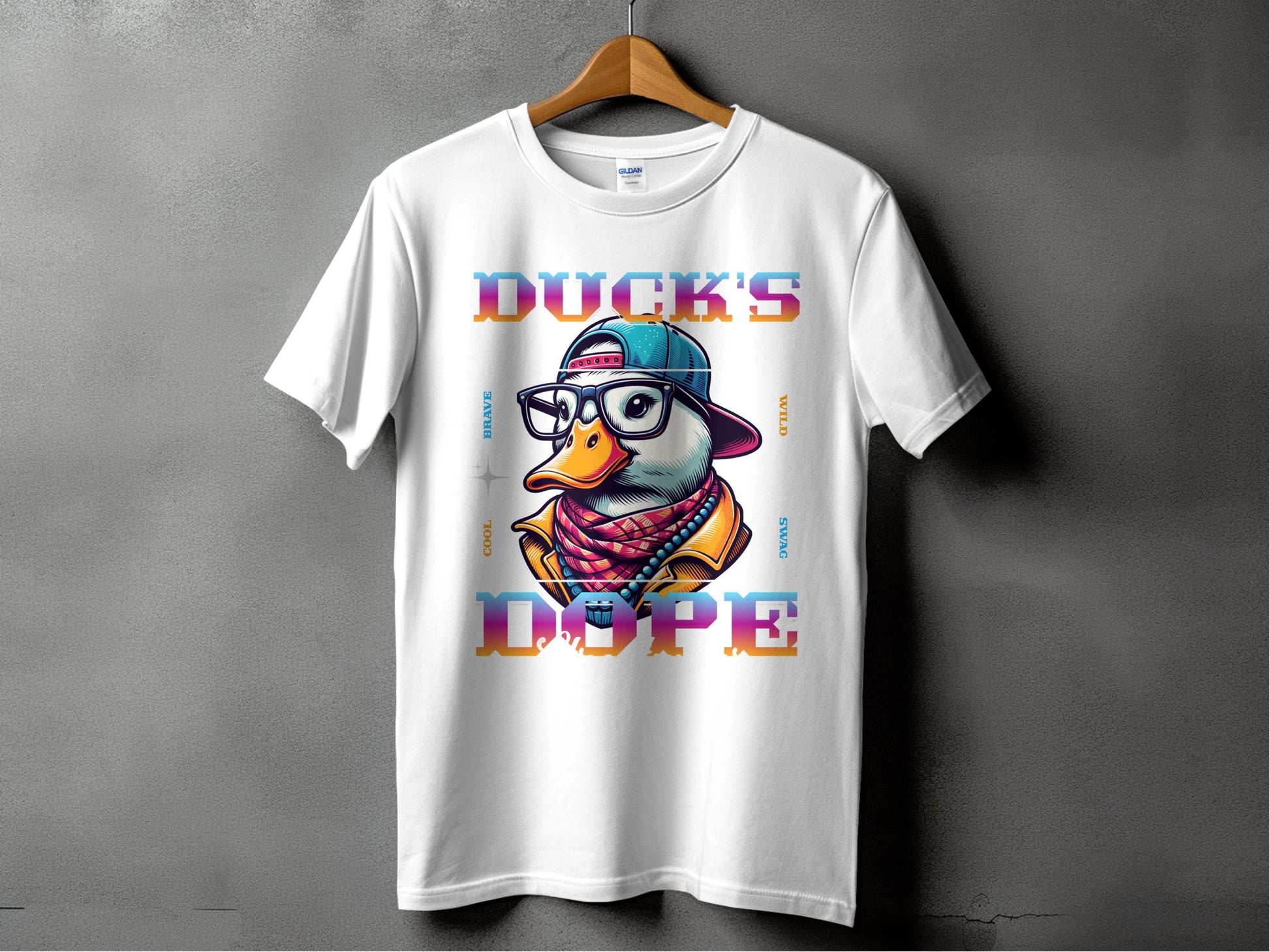 A white t-shirt by Garment Graphics hangs on a wooden hanger against a gray wall, featuring an eye-catching design of a duck with glasses, a cap, and scarf. The words DUCKS DOPE are prominently displayed in bold vibrant letters above and below the duck.