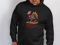 A person dons a Garment Graphics black hoodie with a cartoon turkey and the humorous caption Turkey On The Run against a simple white background, enhancing its charm.