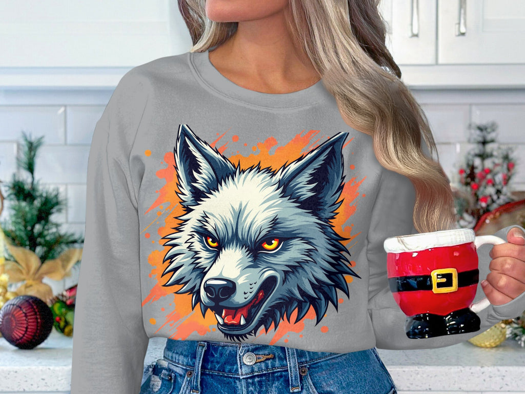 In a kitchen adorned with festive decor, a person with long, wavy hair holds a Santa-themed mug while wearing a bold wolf graphic sweatshirt from Garment Graphics.