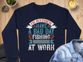 A navy sweatshirt from Garment Graphics says, Id rather have a bad day fishing than a good day at work, displayed on wood with a denim shirt, latte art coffee, and decorative stones nearby.