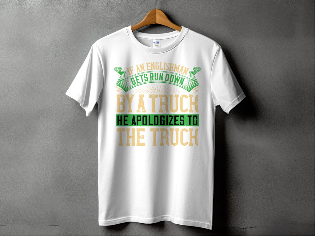 Garment Graphics white T-shirt showcases a clever design with the funny phrase If an Englishman gets run down by a truck, he apologizes to the truck, in green and gold, contrasting attractively against a textured dark gray background.