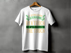 Garment Graphics white T-shirt showcases a clever design with the funny phrase If an Englishman gets run down by a truck, he apologizes to the truck, in green and gold, contrasting attractively against a textured dark gray background.