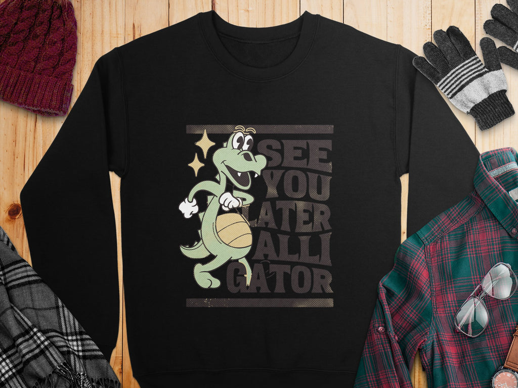 The Garment Graphics sweatshirt showcases a cartoon alligator with a basketball and bold SEE YOU LATER ALLIGATOR text. Pictured on wood, it pairs perfectly with plaid shirts, scarves, gloves, and knit hats—ideal for fans of unique alligator graphic designs!.