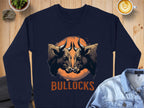 Garment Graphics presents a loose-fit navy sweatshirt featuring eye-catching graphic print: two bulls facing each other over an orange circle with BULLOCKS beneath. Displayed on wood, its paired with a latte and denim shirt.