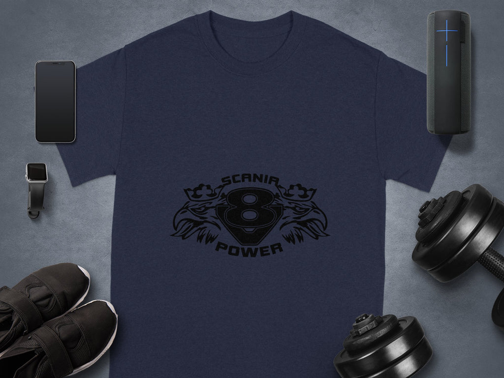 Flat lay featuring a Garment Graphics navy blue T-shirt with Scania Power Eagle and V8 engine design, alongside a smartphone, smart speaker, smartwatch, dumbbells, and black sneakers on a gray surface, highlighting the synergy between tech accessories and graphic design fashion.