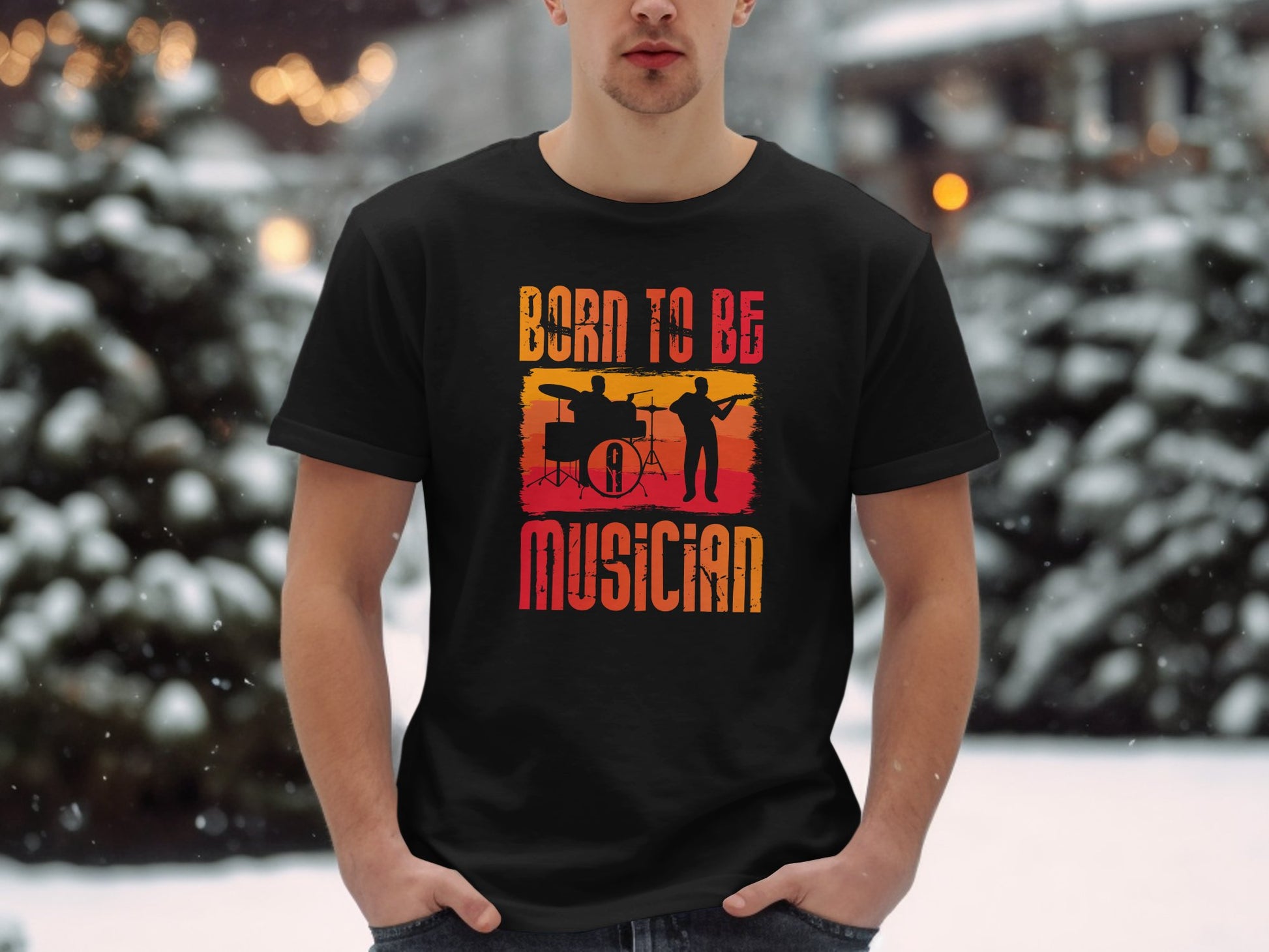 In a snowy outdoor setting, a person wears a black Garment Graphics T-shirt featuring silhouettes of a drummer and guitarist with the text Born to be a musician in a yellow-to-red gradient—ideal for music lovers.