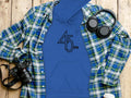 A Garment Graphics Retro Music Hoodie featuring 45 RPM rests under a blue/green plaid shirt on wood, accompanied by a camera, black headphones, and a white coffee cup with lid—ideal for vinyl record enthusiasts.