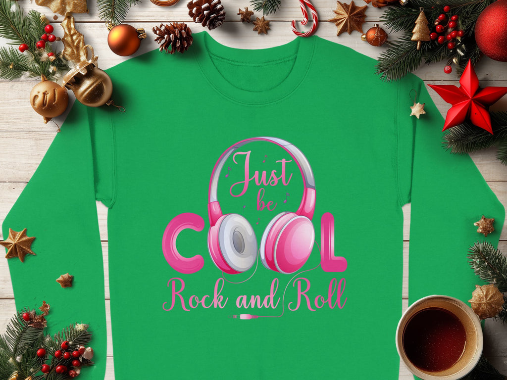 Garment Graphics presents a trendy green shirt with pink and white headphones and the phrase Just be Cool Rock and Roll. Surrounded by festive pine branches, ornaments, a red star, and a cozy coffee cup, its an ideal gift for music lovers.