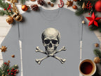 A Garment Graphics gray graphic print sweatshirt featuring a bold skull and crossbones design is displayed on a wooden surface. Its decorated with festive elements like pine branches, ornaments, pine cones, stars, and accompanied by a cup of dark beverage.