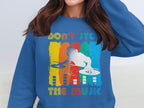 A model wears a blue Garment Graphics sweatshirt featuring a bold DJ design with colorful paint stripes. Dont Stop the Music is printed above and below the DJ silhouette, making it perfect for music lovers who appreciate rhythm and style.