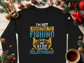 This unisex black sweatshirt by Garment Graphics features the phrase Im not addicted to fishing. We are just in a very committed relationship, surrounded by Christmas decorations and a steaming cup of tea on wood, perfect for any fishing enthusiast.