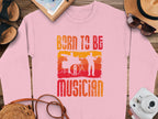 Garment Graphics offers a pink unisex sweatshirt with Born to Be Musician in an orange-red gradient, ideal for music lovers. It features drummer and guitarist silhouettes and can be paired with a notebook, sandals, hat, sunglasses, and purse.