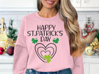 A person in a Garment Graphics sweatshirt featuring Happy St. Patricks Day and a clover design stands in a kitchen adorned with gold and red ornaments, enhancing the holiday cheer.