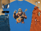 Garment Graphics offers a blue t-shirt for music lovers featuring a gorilla playing an electric guitar and flashing a peace sign. Its styled with jeans, sunglasses, headphones, keys, an orange button-up shirt, and a wristwatch on a wooden surface.