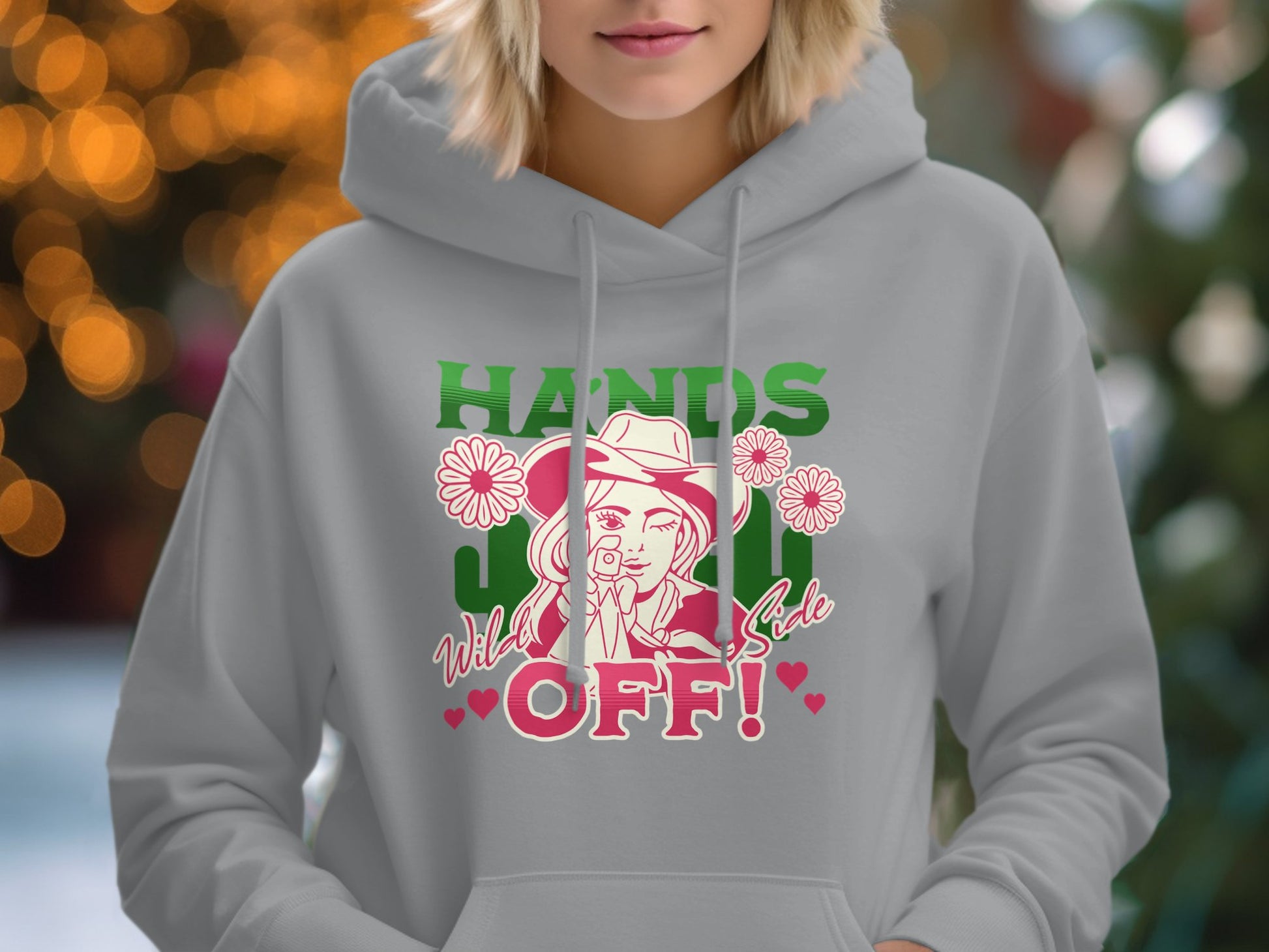 Someone wearing a light gray Garment Graphics Wild Side Hoodie, featuring a cartoon design of a person with a hat and camera surrounded by flowers, along with the text Hands Off! Bold Graphic.