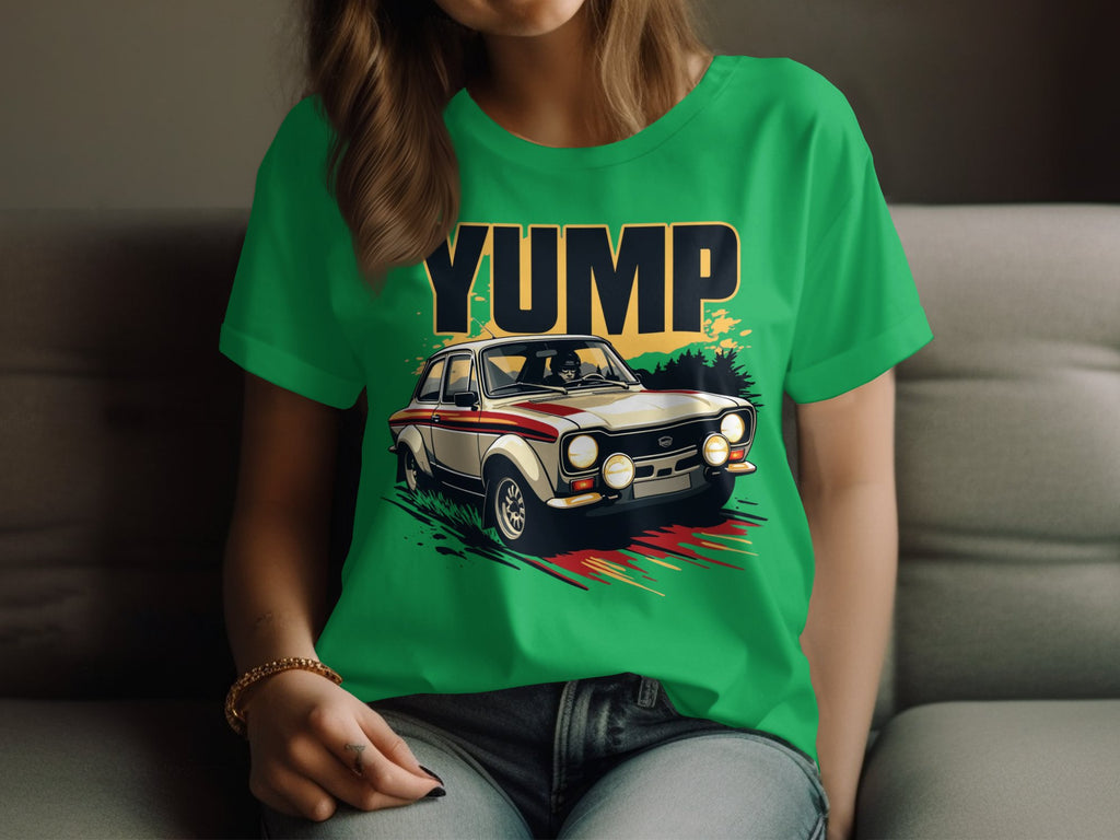 A person lounges on a couch in a green Garment Graphics T-shirt featuring a vintage racing car with the word YUMP in bold letters, stripe details, and large headlights. Theyre paired with jeans and a bracelet.