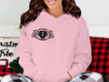 A person in a Garment Graphics pink hoodie, featuring Scania Power, the number 8, and an eye-catching animal design, pairs it with plaid pants in a Christmas-themed room.