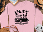 Vintage Ride enthusiasts will love Garment Graphics pink sweatshirt, boasting a classic car graphic with ENJOY Classic CAR, Vintage Ride Community, Aircooled, Estd. 1980. Style it with a straw hat, sunglasses, and a film camera for the perfect nostalgic look.