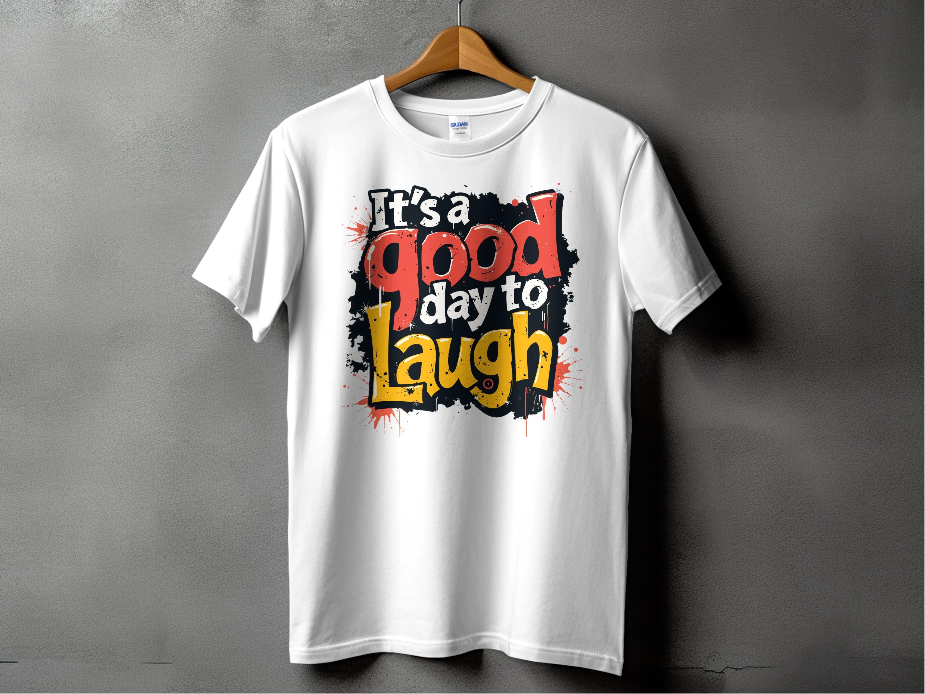 The Its a Good Day to Laugh T-shirt by Garment Graphics hangs on a hanger against a black backdrop, featuring vibrant colors and graffiti-style text for a cheerful touch.